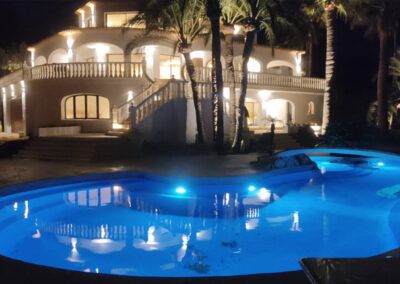 Vista nocturna de un chalet con piscina iluminada